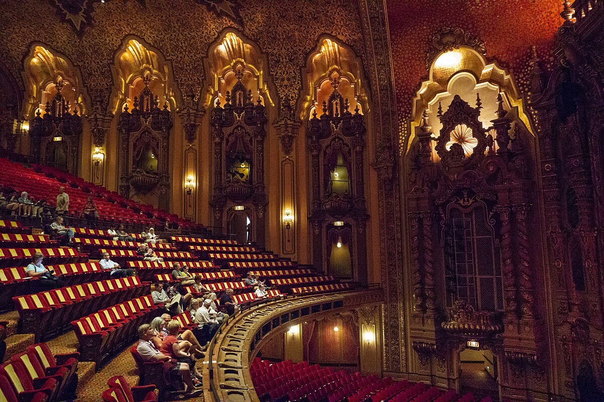 people sitting in audience of large red theatre.